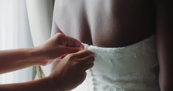 新娘和女朋友一起帮助穿上白色婚纱 住在豪华的宾馆房间里 未婚妻终于为美丽的婚礼做好了准备 — 图库视频影像