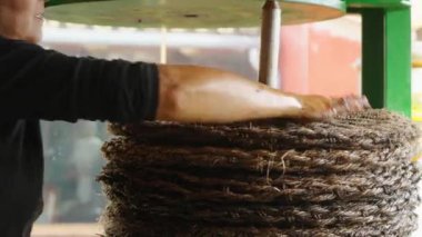 Kadın hasırdan yapılmış tabakları mandıra hamuruyla yapmayı bitiriyor. İşçi inşaat güvenilirliğini test etmeden önce yapının kapağını kapatır