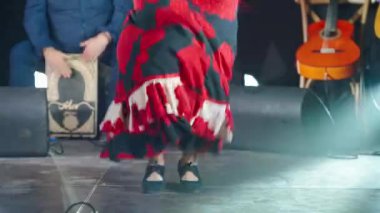 Traje de Gitana 'da kırmızı güllü bir kadın sahnede flamenko çalıyor. Tutkulu bir kadın müzik festivalinde dans ediyor.