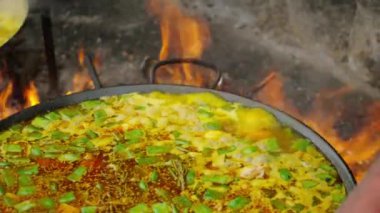 Temiz havada ateşte Paella 'yı kazanda pişirme işlemi. Ulusal İspanyol yemeği insan kültüründe ve geleneklerinde özel rol oynar