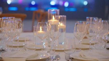 Temiz bardaklar ve restoranda yanan mumlarla şık bir şenlik masası. Lüks bir mekanda romantik bir akşam yemeği.