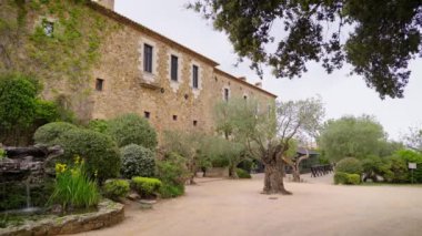 Castell d Emporda Oteli taş cephe ve egzotik bahçe. Eski şatoda turistler süslü düğün törenleri düzenliyor.