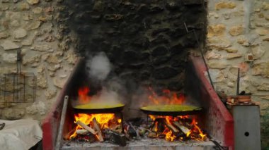 Paella 'yı kâselerde pişirme işlemi gündüz vakti özel fırın ateşinin üzerinde. İşlem sırasında duman yükselir ve en yakın duvara yerleşir. Evi yarı karanlık yapar.