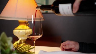 Garson, klasik restoranda misafir bardağına kırmızı şarap dolduruyor. Adam şenlikli romantik randevu için lüks bir içki ısmarlıyor. Sevgililer Günü