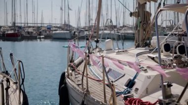 Yatın kenarına asılı bayraklar rüzgarda dalgalanıyor. Deniz marinasında cinsiyet partisi için hazırlanmış bir yat duruyor. Mavi ve pembe balonlarla süslenmiş bir yat.