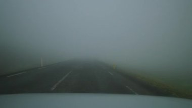 Yağmurlu bir günde araç sisle kaplı yol boyunca gider. Hava koşulları, sürücülerin trafik kazalarını artırması riskini artırıyor.