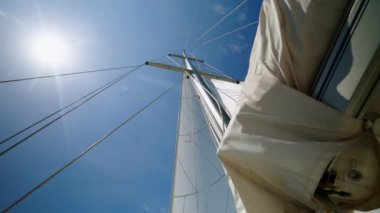 Güverte, hafif esintide kanat çırpan beyaz yelkenleri görüyor. Yelkenler sonsuz denizde yelken açarken kanat çırpar. Parlak güneş ışığında berrak denizin inanılmaz manzarası.