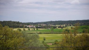 Girona kasabası yakınlarında bulutlu gökyüzünün altında taze tarlalar. Yeşil tarlaları ve uzak Castell d Emporda oteli olan sakin bir yer.