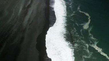 Köpüklü okyanus dalgaları, koyu yüzey hava manzaralı kıyıya doğru yuvarlanıyor. Gök mavisi suların yanında yeşil çimenleri olan yüksek uçurum sakin bir atmosfer yaratır.