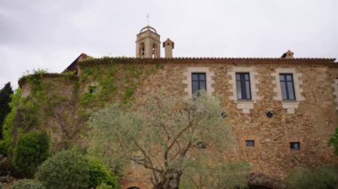 Castell d Emporda Oteli 'nde çan kulesi ve pencereleri olan eski taş cephe kilisesi. İspanya tarihini sunan şaşırtıcı ortaçağ mimari mirası