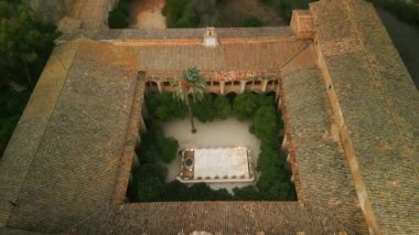 Eski taş sahneli havadan manzaralı portakal ağaçları avlusu. Sant Jeroni de Cotalba Kraliyet Manastırı 'nın antik mimarisi ve yaz doğası.