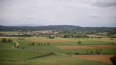 Bulutlu gökyüzü manzaralı Girona kasabasına karşı yeşil tarlalar. Tarlaları ve ortaçağ Castell d Emporda 'sı olan resimli bir manzara.