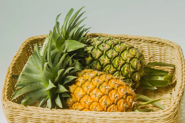 Two  ripe pineapples in basket on white background