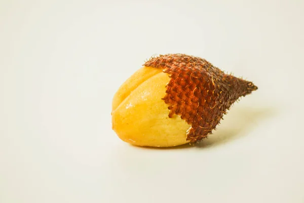 Snake fruit is a fruit that has a sweet and sour taste. Peel one fruit on a white background.