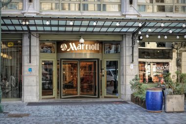 Brüksel Merkezi 'ndeki bir Marriott otelinin girişinde cam bir kapı ve önemli bir Marriott logosu var. Ön cephe dekoratif ışıklandırma ve saksı bitkileriyle modern..