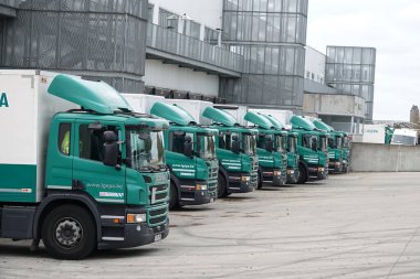 Yükleme alanına park etmiş bir dizi yeşil Igepa nakliye kamyonu. Kamyonlar aerodinamik tasarımlarını ve markalarını sergiliyorlar..