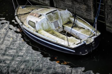 Gent Flanders Belgium 11 16 2024 An abandoned, weathered sailboat with moss and dirt on its surface, docked in a murky water canal. The boat appears neglected, with visible signs of decay clipart