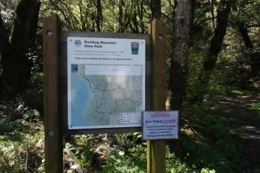 Humbug Dağı, Orford Limanı, Oregon 05 09 2024 Humbug Dağı Eyalet Parkı 'nda verimli ormanlarla çevrili bir patika haritası ve bilgi panosu. Tahtada patikaların bir haritası var.