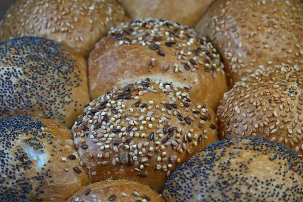 Üzerine susam, haşhaş ve karışık tahıllar da dahil olmak üzere çeşitli tohumlar serpiştirilmiş taze fırın rulolarından oluşan genel bir çekim..
