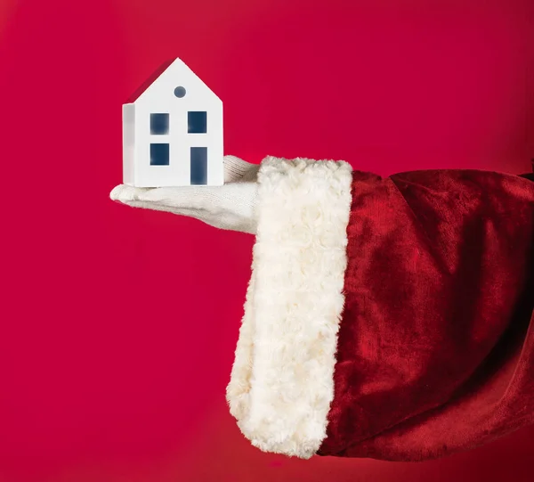 Geleneksel kırmızı Noel Baba kostümü içinde beyaz bir ev modeli barındırıyor. Gayrimenkul, Ev Mülkü Satılık ve Kira - fotokopi alanı, tanıtım tasarımı reklamı.
