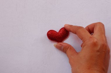 Female hand giving red mini heart on paper white pattern butiful background. clipart