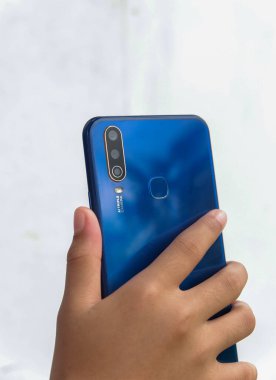 Küçük bir Asyalı çocuğun elinde mavi bir akıllı telefon tutarken fotoğrafı.