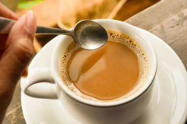 Bir fincan sütlü kahve fotoğrafı. Beyaz seramik bardak. Düz yatıyordu