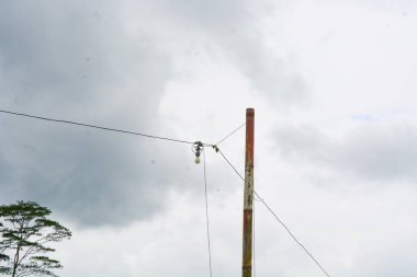Yolun kenarındaki elektrik direğinin alçak açılı fotoğrafı. Açık gökyüzü manzaralı. Kimse yok.