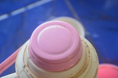 Açık kahverengi vücut rengi ve pembe kapaklı termosun yakın görüntüsü. Kimse yok..