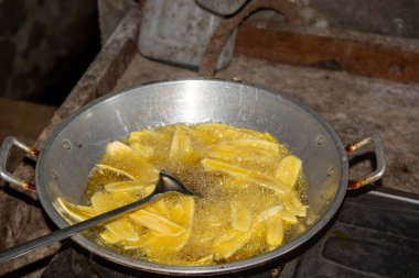 Büyük bir tavada kızgın yağlı muz cipsi kızartma işlemi..