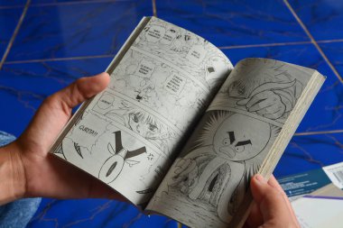 29 Mayıs 2023. Evin verandasında çizgi roman okuyan bir kadın. Wonosobo, Endonezya. Endonezya