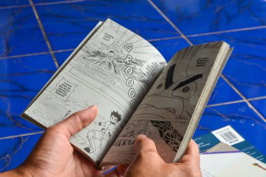 29 Mayıs 2023. Evin verandasında çizgi roman okuyan bir kadın. Wonosobo, Endonezya. Endonezya