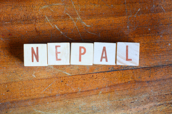 Фотография слов с деревянными блочными объектами, расположенными в слово "НЕПАЛ" на английском языке