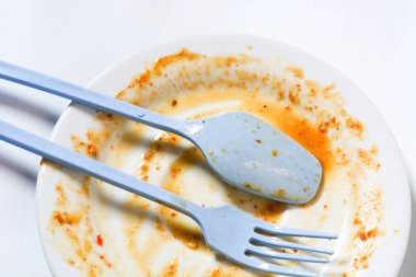 Kirli boş tabak, çatal ve bıçak beyaz tabakta. Çatal bıçak takımı kullanılmış, yemeğin ya da öğle yemeğinin sonunu simgeliyor..