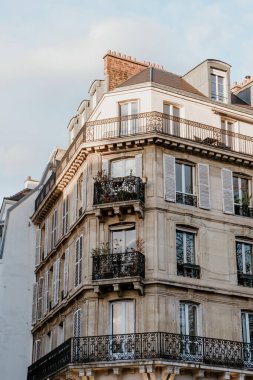 Fransa 'nın başkenti Paris' te bulunan bej renkli, cam pencereli ve güzel dökme demir balkonlu yaşlanmış konut binasının dışı.