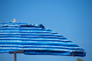 Mavi gökyüzüne karşı mavi kumsal şemsiyesi