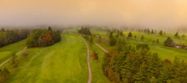 Güzel bir sonbahar gününde bir sürü ağacın olduğu bir golf sahasının havadan görünüşü.