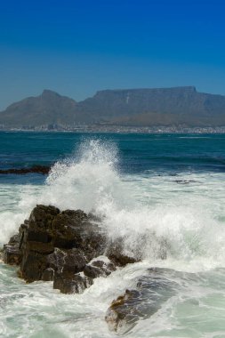 Cape Town 'daki kayalıklara çarpan dalgaların ve Güney Afrika' daki Robben Adası 'ndaki Masa' nın manzarası.