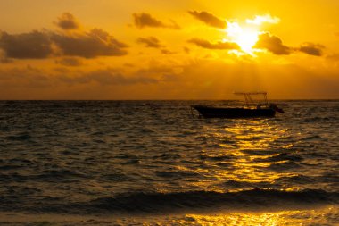 Gün batımında denizdeki balıkçı teknesinin silueti. 