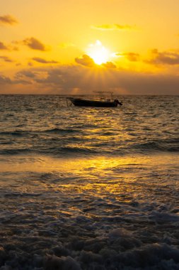 Gün batımında denizdeki balıkçı teknesinin silueti. 
