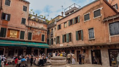 Venedik, İtalya. Piazza del Campo 'daki eski binanın yakınındaki bir kafede insanlar. 
