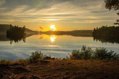 Kanada ormanında muhteşem bir balıkçı gölünün üzerinde gün batımı