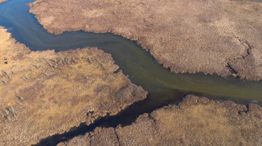 Dolambaçlı bir nehir ile manzaralı bir manzarayı vurgulayan bir hava manzarası.