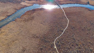 Dolambaçlı bir nehir ile manzaralı bir manzarayı vurgulayan bir hava manzarası.