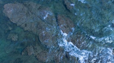 Dalgalar ve kayalarla deniz suyu yüzeyinin havadan görünüşü. en üstteki görünüm.