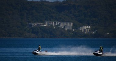 İki adam su motorlu scooterlara biniyor.