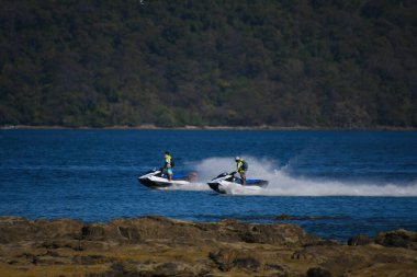 İki adam su motorlu scooterlara biniyor.