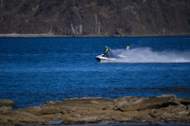 İki adam su motorlu scooterlara biniyor.