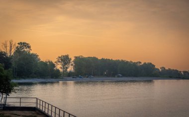 Gün batımı gökyüzü nehir ve adanın üzerinde ağaçlarla 