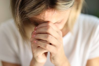 Genç bir kadının el ele tutuşup evde yalnız dua etmesi. İnanç, maneviyat ve din kavramı